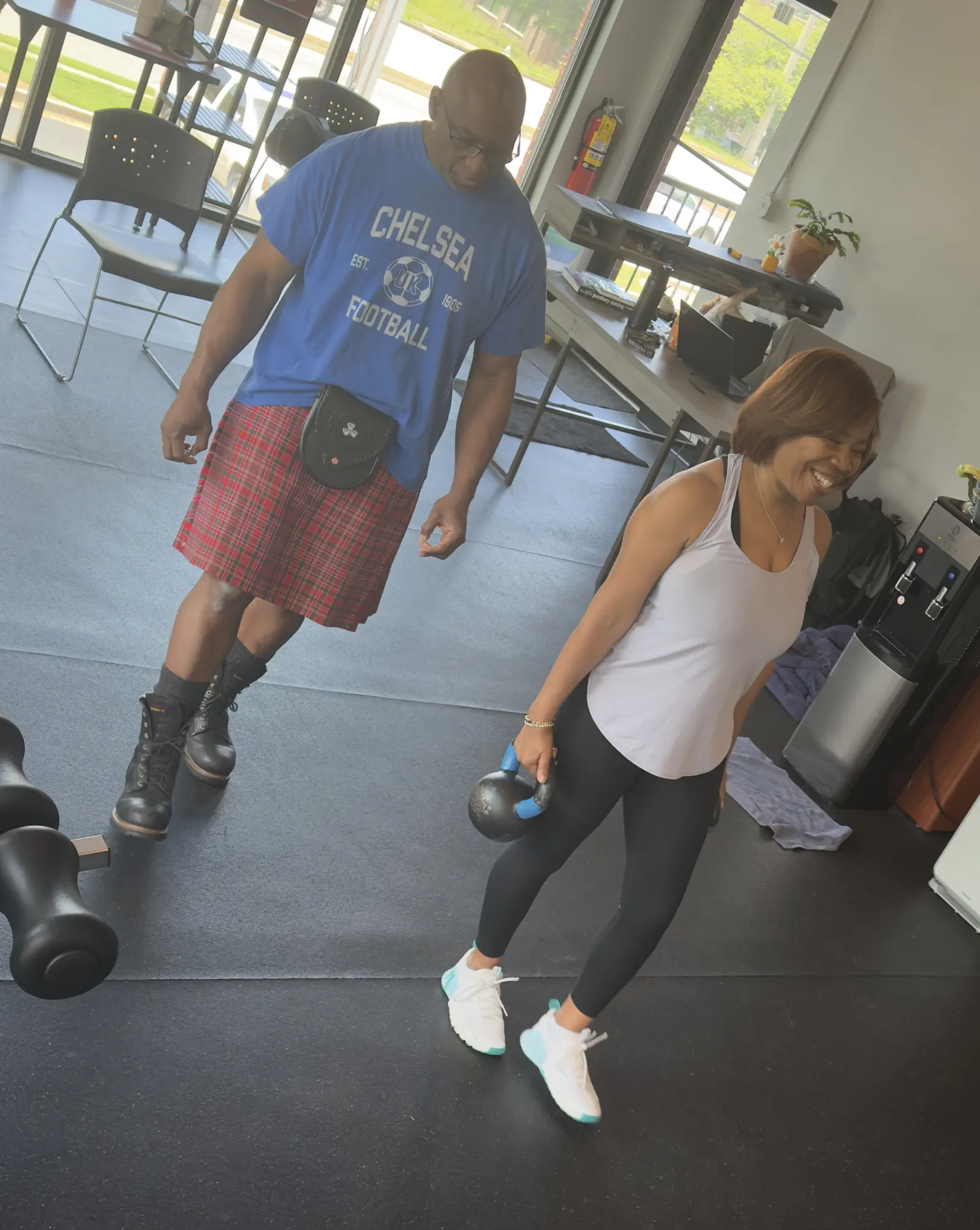 A McCallister Fitness coach guiding a client through kettlebell training in the studio
